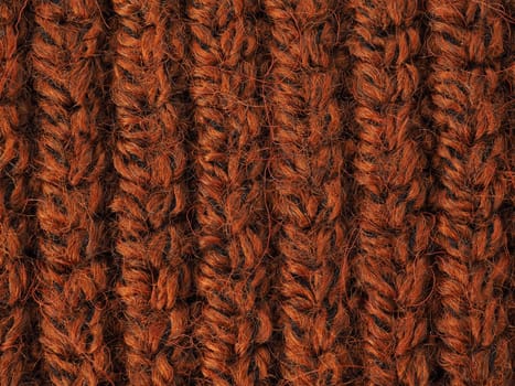 Orange knitted material background. A beautiful closeup of a hand knitted warm and soft wool pattern. Texture of a brown sweater, socks or scarf .