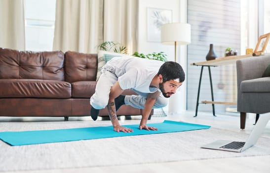 Whatever the problem, yoga is the solution. a man using his laptop while practising yoga at home