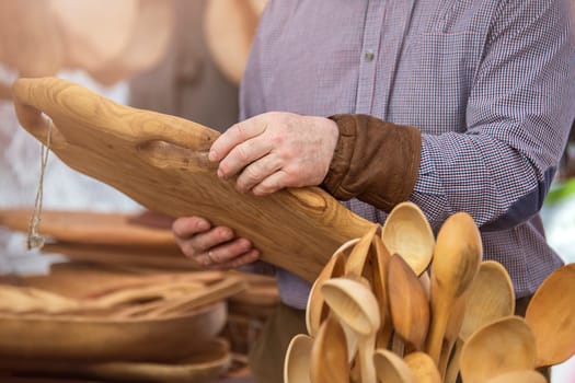 Production of wooden products in the concept of small business. Carpenter holding a rare wood tray in a carpentry workshop. Manufacture and sale of wooden furniture. High quality photo