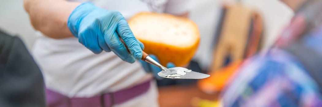 A man gives a cheese tasting to his customer. Cheese tasting. Cheese is cut with a special cheese knife. High quality photo