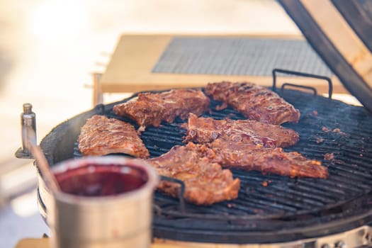 The process of grilling ribs. A man turns a piece of grilled ribs with tongs while grilling meat. This is the season for barbecues and outdoor cooking. High quality photo