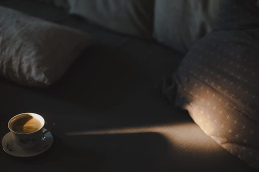 Coffee in a cozy interior home background, Lifestyle concept. Soft light of the rising sun came through the window to a cup of coffee on bed.