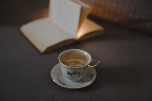 Coffee and a book in a cozy interior home background, Lifestyle concept. Soft light of the rising sun came through the window to a cup of coffee and a book on bed.