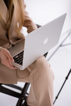 A business woman in a suit is working, typing on a laptop close-up and sitting on a chair. Close-up of hands with computer, Vertical