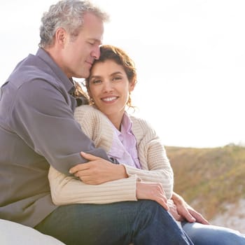 Appreciating one another. A mature couple hugging one another while sitting on a sand dune