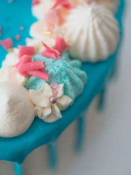 studio shot of chocolate frosted blue dripped icing white cup cake, unicorn , meringue and sprinkles on top