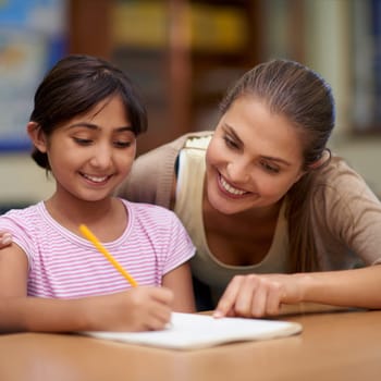 School, education or learning with a student and teacher in a classroom together for writing or child development. Study, scholarship and teaching with a woman educator helping a girl child in class.