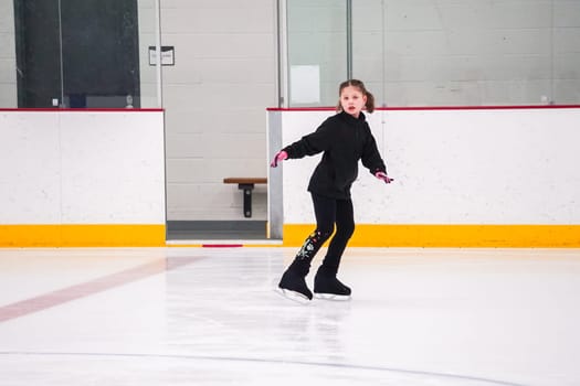 Little girl practicing figure skating at the indoor ice rink.