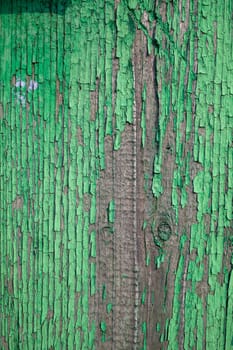 Wood texture with green flaked paint. Peeling paint on weathered wood. Old cracked paint pattern on rusty background. Chapped paint on an old wooden surface