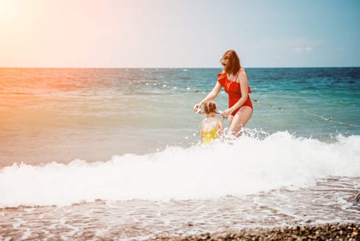 Happy loving family mother and daughter having fun together on the beach. Mum playing with her kid in holiday vacation next to the ocean - Family lifestyle and love concept.