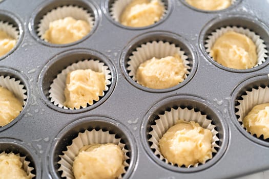 Scooping cupcake batter with dough scoop into a baking pan with liners to bake American flag mini cupcakes.