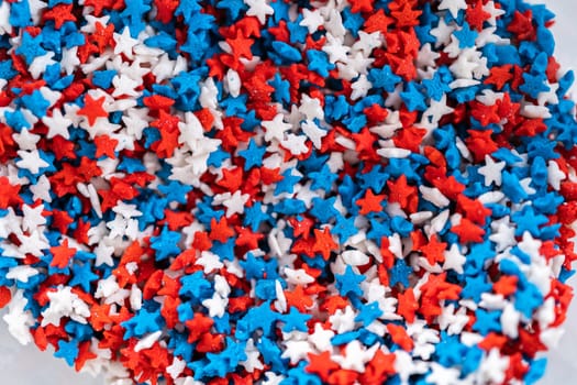 Star-shaped white, red, and blue sprinkles in a glass pinch bowl.