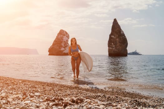 Close up shot of beautiful young caucasian woman with black hair and freckles looking at camera and smiling. Cute woman portrait in a pink bikini posing on a volcanic rock high above the sea