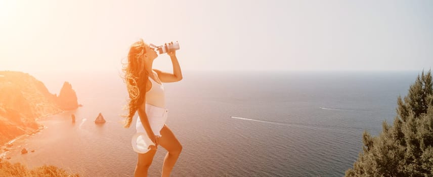 Woman travel sea. Young Happy woman in a long red dress posing on a beach near the sea on background of volcanic rocks, like in Iceland, sharing travel adventure journey