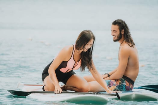 Sea woman and man on sup. Silhouette of happy young woman and man, surfing on SUP board, confident paddling through water surface. Idyllic sunset. Active lifestyle at sea or river