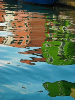 The characteristic colored houses of Burano (Venice) reflected on the water of a canal