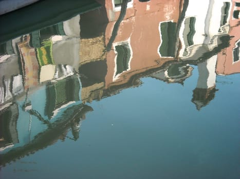 The characteristic colored houses of Burano (Venice) reflected on the water of a canal