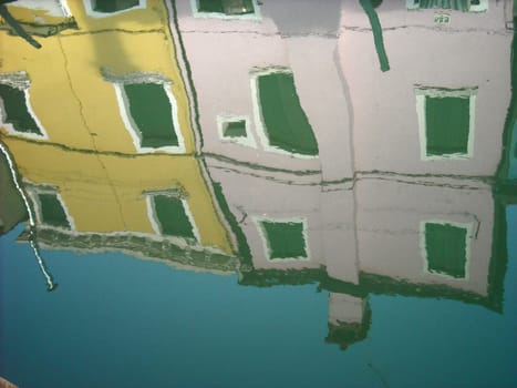 The characteristic colored houses of Burano (Venice) reflected on the water of a canal