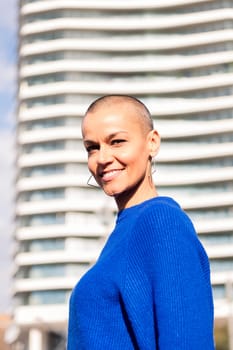 empowered woman with bald head smiling looking at camera, concept of urban lifestyle and rebel style, copy space for text