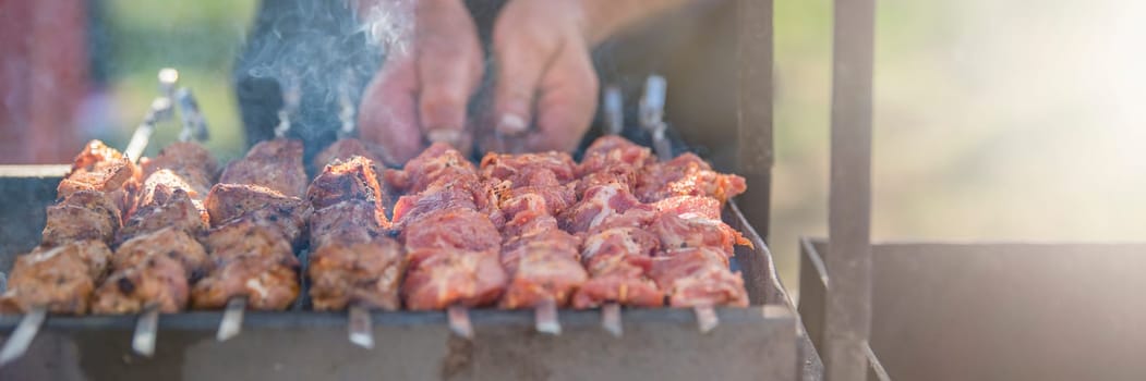 A man fries kebabs on the grill on a sunny day. Organization of a picnic in nature. High quality photo