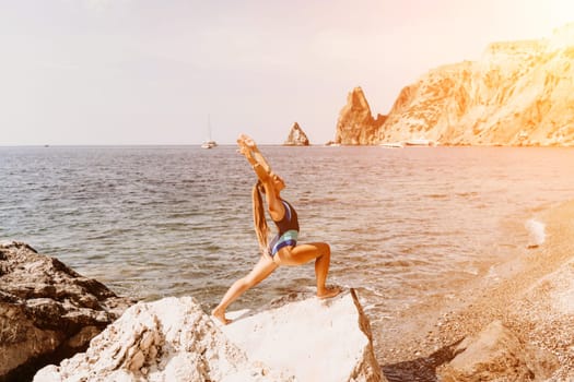 Yoga on the beach. A happy woman meditating in a yoga pose on the beach, surrounded by the ocean and rock mountains, promoting a healthy lifestyle outdoors in nature, and inspiring fitness concept