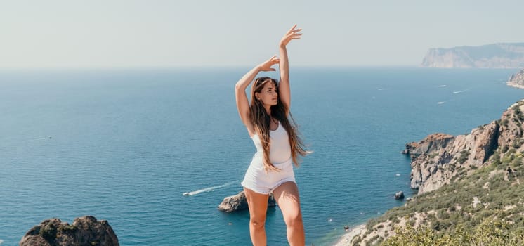 Woman travel sea. Young Happy woman in a long red dress posing on a beach near the sea on background of volcanic rocks, like in Iceland, sharing travel adventure journey