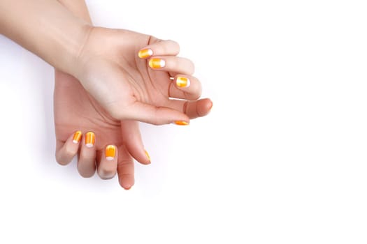 Beautiful Female Hands with bright Orange Manicure like Candy Corn on White Background. Manicured Nails with Creative Gel Polish Design. Halloween Style