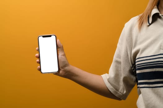 Woman hand holding smartphone on yellow background. Blank screen for your application design.