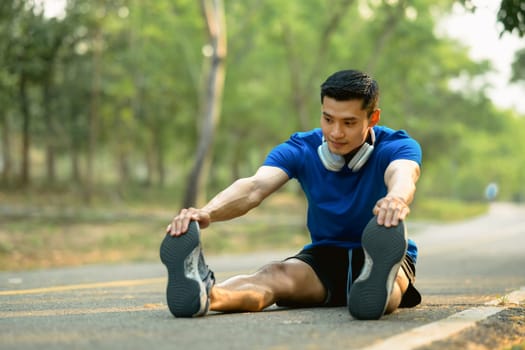 Athletic man stretching his muscular before before running in the morning. Fitness, sport and healthy lifestyle concept.