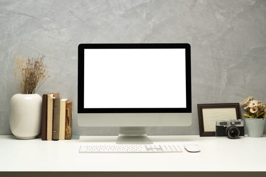 Stylish workplace with blank screen computer, picture frame and books. Empty screen for montage your graphic display.