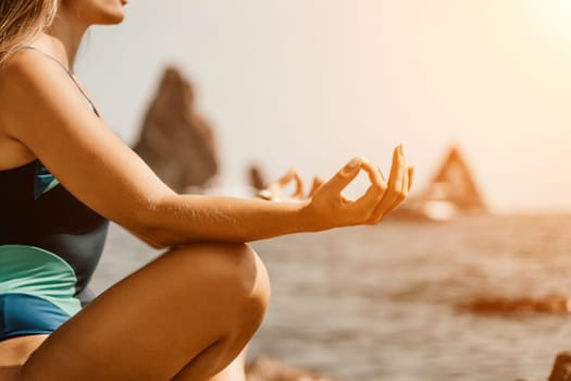 Yoga on the beach. A happy woman meditating in a yoga pose on the beach, surrounded by the ocean and rock mountains, promoting a healthy lifestyle outdoors in nature, and inspiring fitness concept