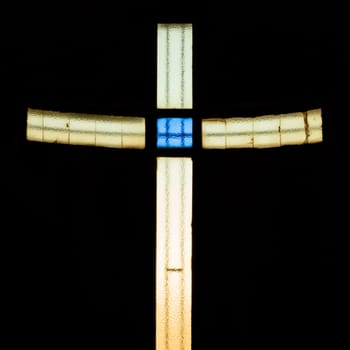 Stained glass cross in bright vivid colors in a church. Ideal for events, concepts and backgrounds.