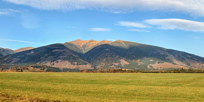 High resolution panorama of Western Tatras (Zapadne Tatry, Liptov region) with mount Baranec peak, green meadow in foreground, on clear autumn day.