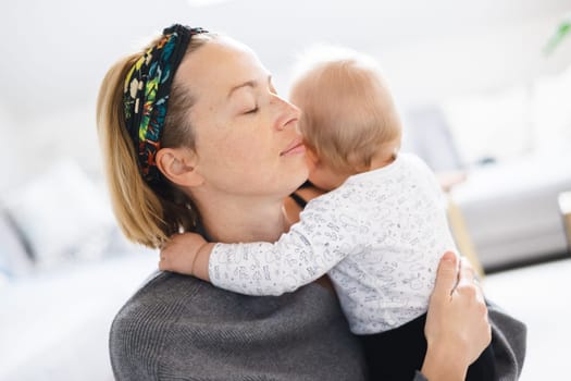 Tender woman caressing her little baby boy infant child outdoors. Mother's unconditional love for her child.