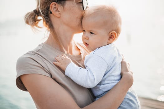 Tender woman caressing her little baby boy infant child outdoors. Mother's unconditional love for her child.