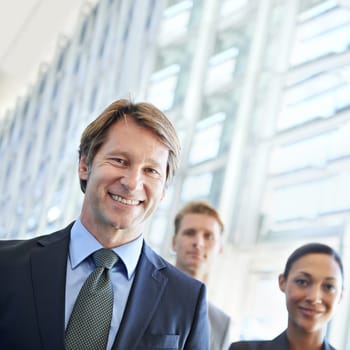 Hes an excellent leader. Portrait of a mature businessman with his colleagues standing in the background