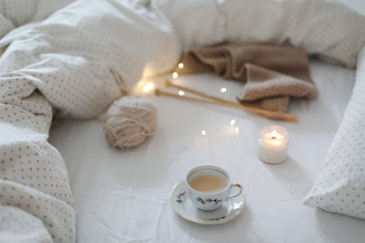 yarn and a cup of coffee on the bed. Hygge lifestyle, cozy mood. Handicraft day concept.