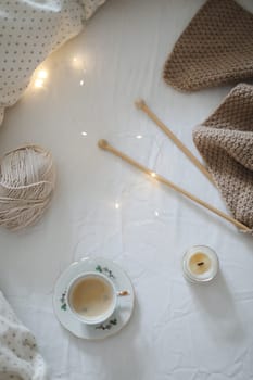 yarn and a cup of coffee on the bed. Hygge lifestyle, cozy mood. Handicraft day concept.