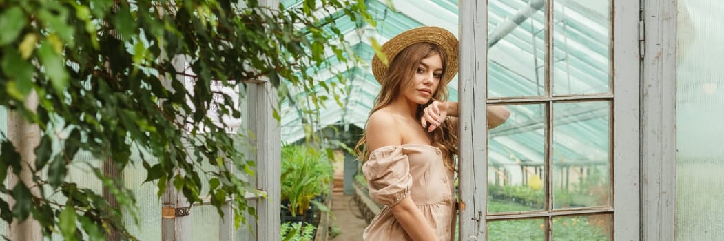A beautiful young woman takes care of plants in a greenhouse. The concept of gardening and an eco-friendly lifestyle