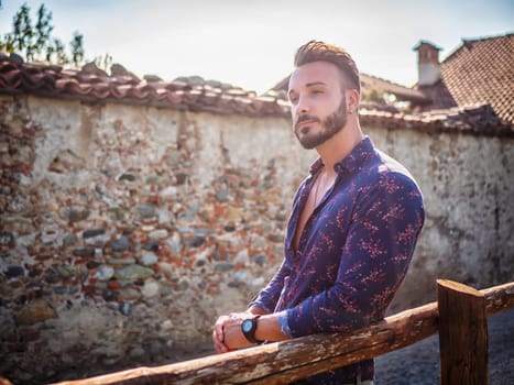 Handsome Hunky Young Man Outdoor in Countryside Leaning on Wood Fence, While Looking away