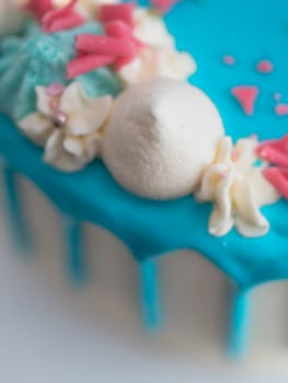 studio shot of chocolate frosted blue dripped icing white cup cake, unicorn , meringue and sprinkles on top