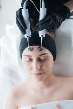 Young caucasian woman on microcurrent therapy procedure. Beautician's office