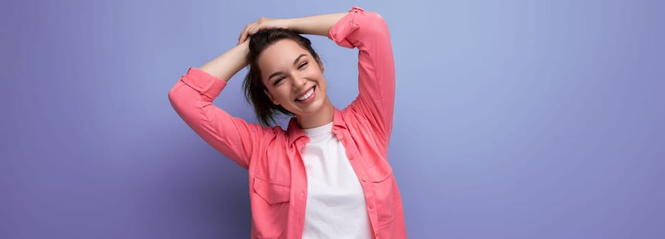 panoramic photo of a young brunette woman in a pink shirt with a Hollywood smile on a studio background.