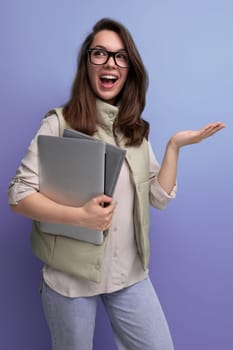 confident 30s female office worker with a stack of documents and a laptop in her hands.