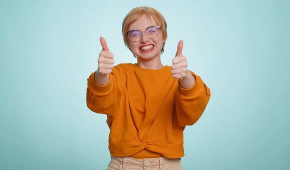Happy joyful woman shouting, raising fists in gesture I did it, celebrating success, winning, birthday, lottery jackpot goal achievemen, good news. Young blonde girl on blue studio wall background