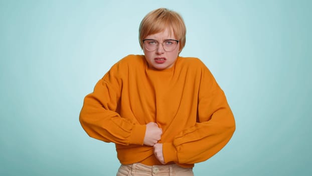 Young woman in sweater screams yell from stress tension problems feels horror hopelessness fear panic surprise shock expresses gestures rage. Pretty blonde girl isolated on blue studio background