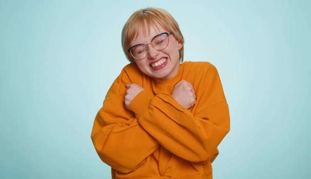 Come to me I want to embrace you. Young happy woman in glasses spread hands and give hug to you. Pleasant expression love feelings. Blonde short haired girl isolated on blue studio background, indoors