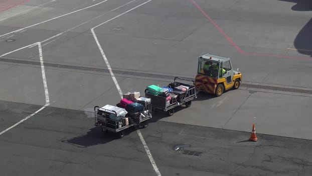 Trailer truck full of suitcases on the runway. Workers carry suitcases to load on the plane. 4k