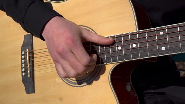 A young man plays the acoustic guitar. Close-up of a hand striking a string. 4k