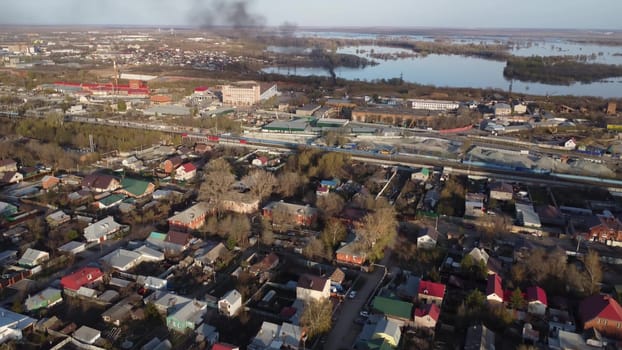 Cottage houses top view from a drone. Flight over the city. There is black smoke near the river. 4k